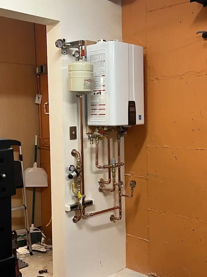 Plumbing technician inspecting water heater connections in Kirtland